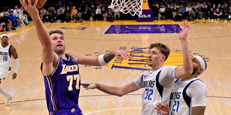 Nov 28, 2025; Los Angeles, California, USA;  Los Angeles Lakers guard Luka Doncic (77) drives past Dallas Mavericks forward Cooper Flagg (32) and forward Daniel Gafford (21) in the first half at Crypto.com Arena. Mandatory Credit: Jayne Kamin-Oncea-Imagn Images