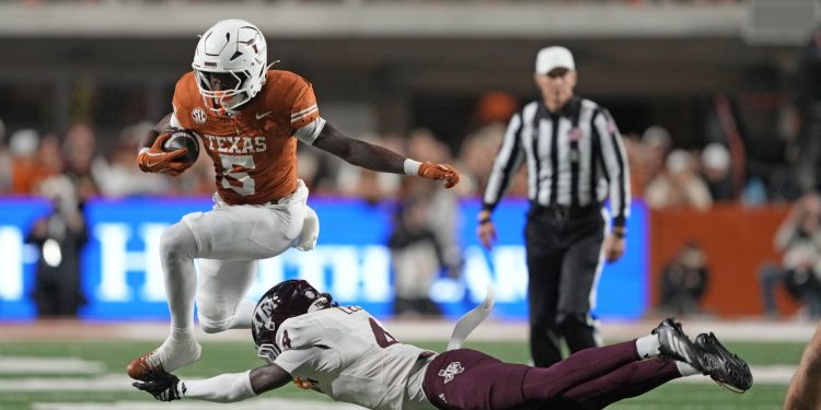 Nov 28, 2025; Austin, Texas, USA; Texas Longhorns running back Quintrevion Wisner (5) leaps over Texas A&M Aggies cornerback Will Lee III (4) during the first half against the Texas Longhorns at Darrell K Royal-Texas Memorial Stadium. Mandatory Credit: Scott Wachter-Imagn Images