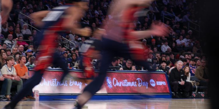 Dec 25, 2025; New York, New York, USA; Players run up court in front of a Christmas Day display board during the first quarter between the New York Knicks and the Cleveland Cavaliers at Madison Square Garden. Mandatory Credit: Vincent Carchietta-Imagn Images