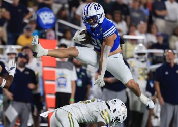 Dec 27, 2025; Orlando, FL, USA; BYU Cougars running back Enoch Nawahine (21) jumps over Georgia Tech Yellow Jackets defensive back Omar Daniels (9) during the second half at Camping World Stadium. Mandatory Credit: Kim Klement Neitzel-Imagn Images