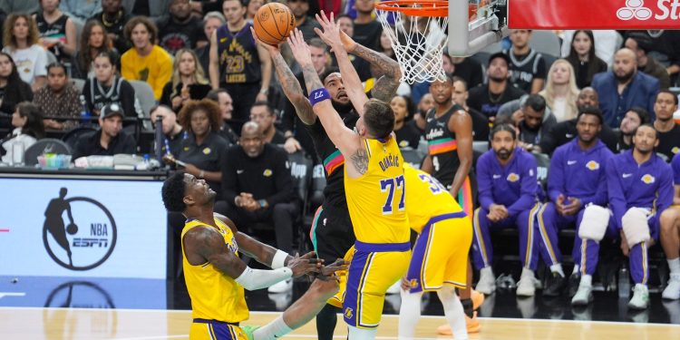 Jan 7, 2026; San Antonio, Texas, USA;  San Antonio Spurs forward Julian Champagnie (30) shoots against Los Angeles Lakers forward/guard Luka Dončić (77) in the second half at Frost Bank Center. Mandatory Credit: Daniel Dunn-Imagn Images