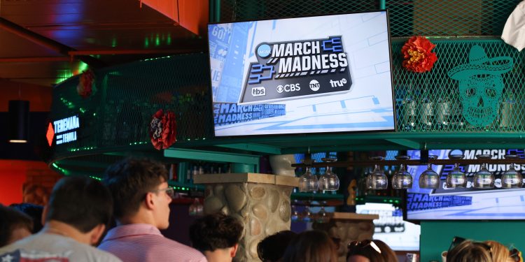 A screen at Miguel's Mexican Cocina & Bar in Lubbock shows the NCAA March Madness logo as Texas Tech students and men's basketball fans watch the Red Raiders take on the Florida Gators in the 2025 NCAA March Madness Elite Eight round on March 29, 2025 in Lubbock, Texas. © Mateo Rosiles/ Avalanche-Journal / USA TODAY NETWORK via Imagn Images