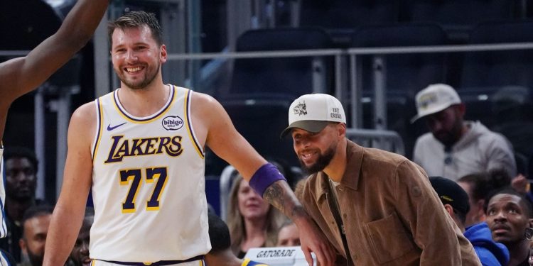 Feb 28, 2026; San Francisco, California, USA;  Injured Golden State Warriors guard Stephen Curry (30) laughs with Los Angeles Lakers forward/guard Luka Doncic (77) in the third period at Chase Center. Mandatory Credit: David Gonzales-Imagn Images
