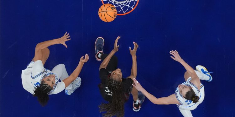 From left, UCLA center Lauren Betts (51), South Carolina forward Maryam Dauda (30) and UCLA forward Angela Dugalic (32) battle for a rebound during the first half of the women's National Championship Final Four NCAA college basketball tournament game, Sunday, April 5, 2026, in Phoenix. (AP Photo/Ross D. Franklin)