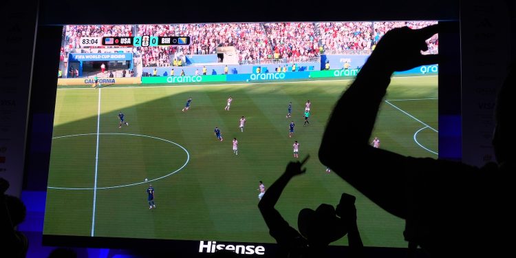 Soccer fans, including Caleb Triana, wearing a cowboy hat, celebrate the U.S. scoring its second goal as they watch a live broadcast of the World Cup round of 32 soccer match between the United States and Bosnia, Wednesday, July 1, 2026, at an official fan fest in downtown Miami. (AP Photo/Rebecca Blackwell)