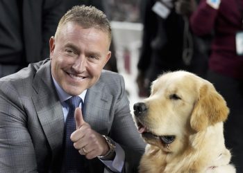 ESPN's Kirk Herbstreit, left, poses with his dog Peter before the start of an NCAA college football game between Texas and Texas A&M on Saturday, Nov. 30, 2024, in College Station, Texas. (AP Photo/Sam Craft)