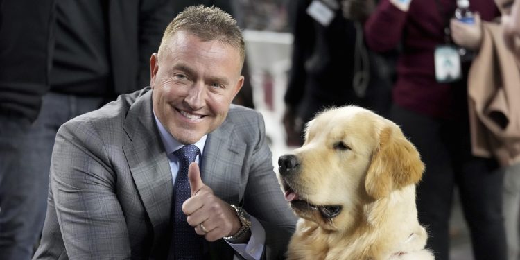 ESPN's Kirk Herbstreit, left, poses with his dog Peter before the start of an NCAA college football game between Texas and Texas A&M on Saturday, Nov. 30, 2024, in College Station, Texas. (AP Photo/Sam Craft)